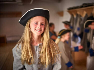 Tourisme Montérégie | Enfant souriant avec chapeau historique